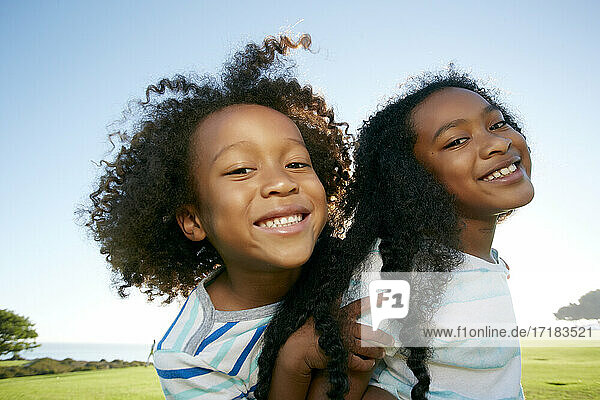 Junge gemischte Rasse Mädchen gibt ihr jüngerer Bruder ein Huckepack Lift