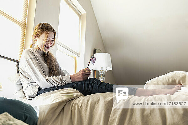 Teenager-Mädchen auf dem Bett liegend mit ihrem Smartphone