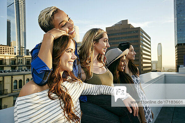 Eine Gruppe junger Frauen  die in der Abenddämmerung auf dem Dach einer Stadt feiern