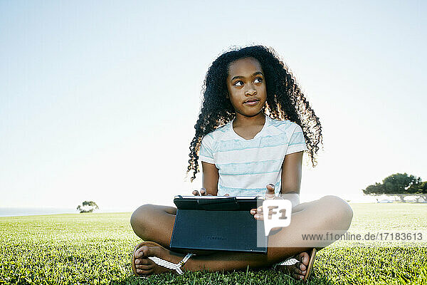 Neun Jahre altes gemischtrassiges Mädchen im Freien mit einem digitalen Tablet.