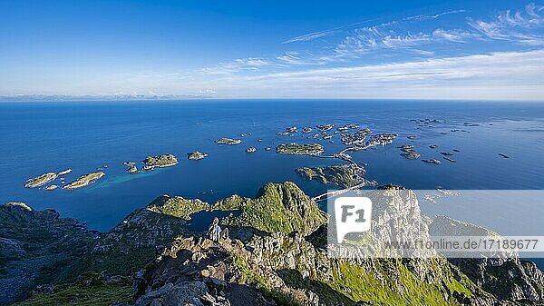 Kleine Felsinseln im Meer  Wanderin blickt vom Gipfel des Berges Festvågtind auf OrtHenningsvær  Vågan  Lofoten  Nordland  Norwegen  Europa