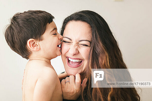 Ein Kleinkind küsst seine Mutter auf die Wange  die Mutter lacht.