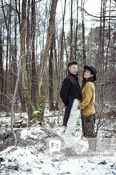 seltsames weibliches Paar lächelt zusammen im schneebedeckten Wald