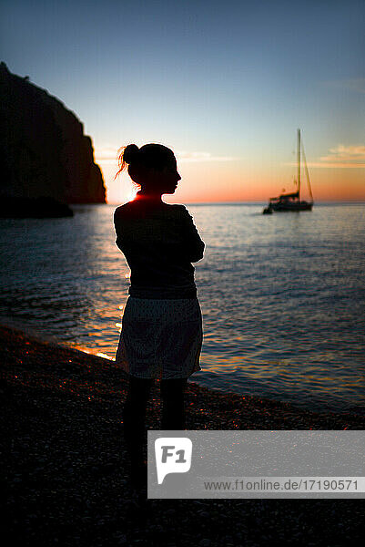 Silhouette einer nachdenklichen jungen Frau  die einen schönen Sonnenuntergang genießt