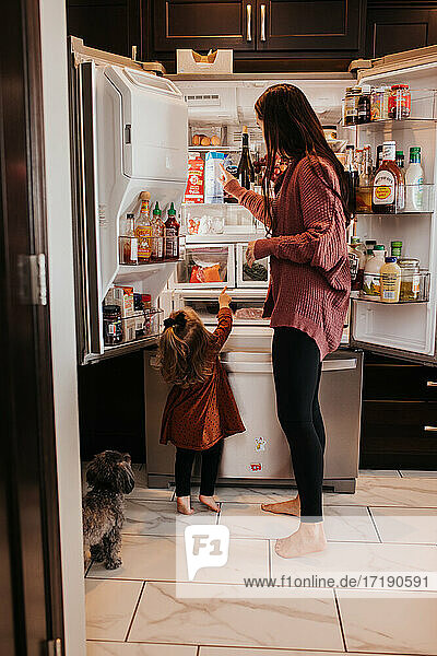 Kleinkind zeigt auf das  was es aus dem Familienkühlschrank in der Küche haben möchte