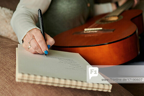 Nahaufnahme einer Frau mittleren Alters  die in ein Notizbuch schreibt. Musik lernen