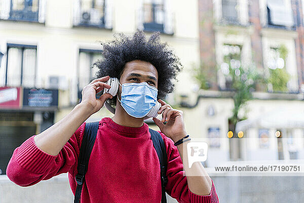 young man with afro hair listening to music from his smartphone