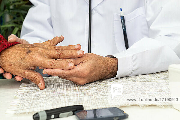 Arzt untersucht die Hand eines älteren Mannes mit Osteoarthritis
