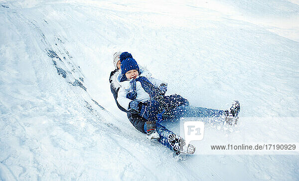 Mother and child tobogganing in winter