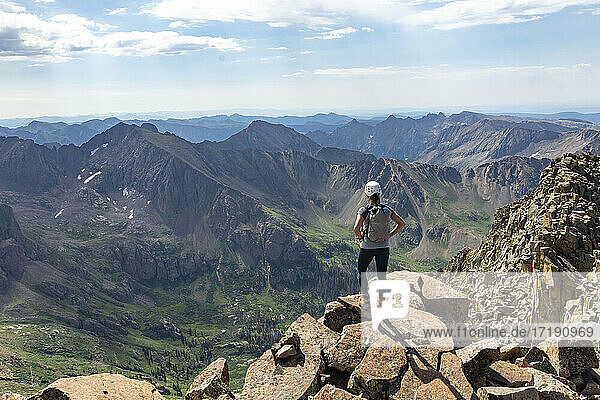 Rückansicht einer Frau  die auf einem Berg stehend die Aussicht betrachtet