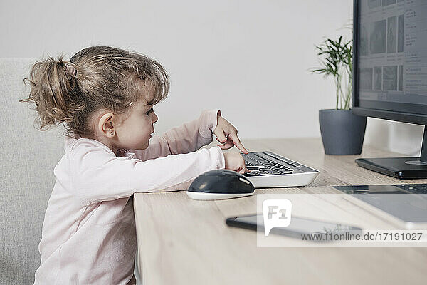 Ein 2-jähriges Mädchen benutzt eine Computertastatur  während es in einem Bürostuhl sitzt