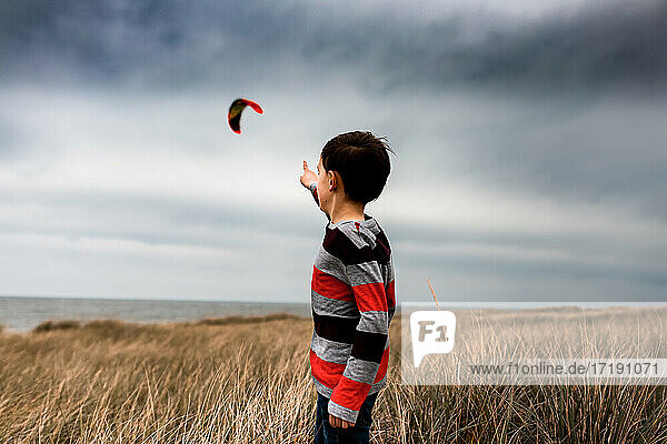 boy pointing to kite surfer in the clouds on a beach in Lake Michigan