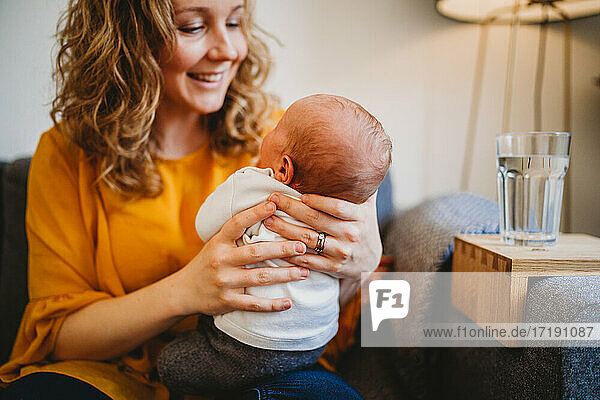 Schöne weiße blonde Mutter lächelnd auf ihr neugeborenes Baby zu Hause