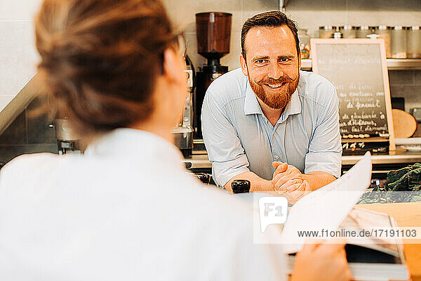 Restaurant lifestyle. Male chef at bar counter smiling at client