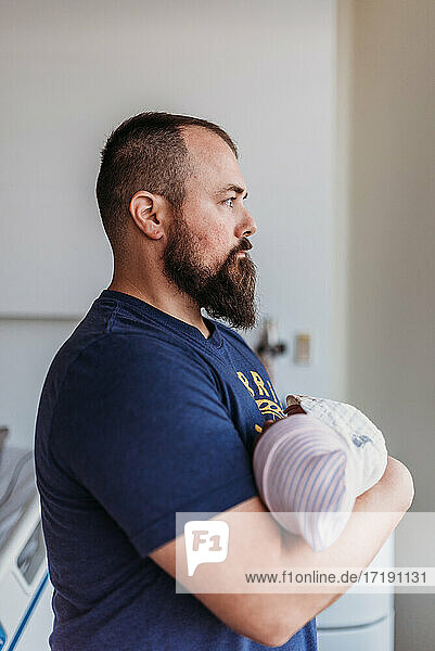 Newborn baby boy being held by father in birthing center after birth