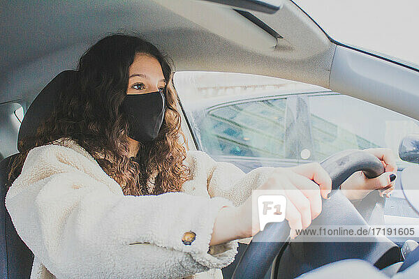 young woman driving with protective mask