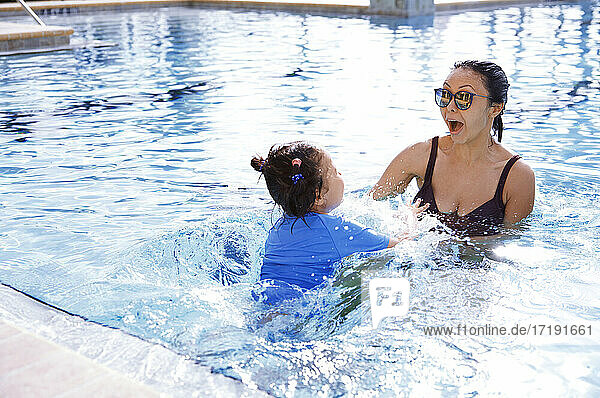 Mother and daughter having fun in swimming pool