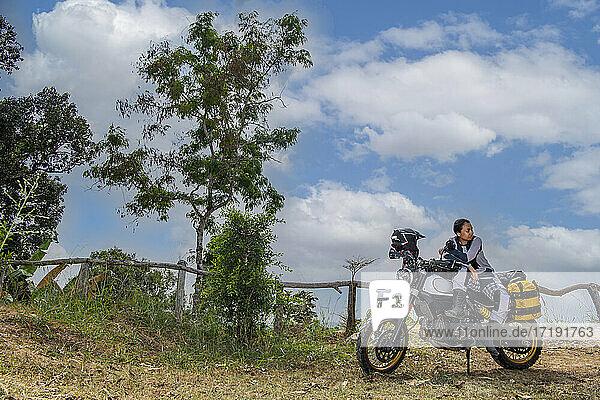 Frau posiert auf einem Geländemotorrad vom Typ Scrambler in Thailand
