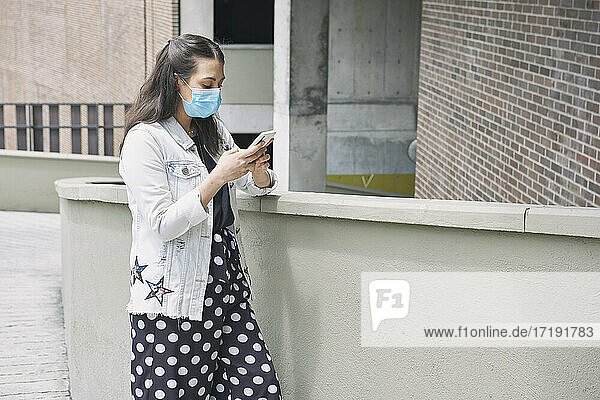Eine attraktive hispanische Frau mit einer Gesichtsmaske  die im Freien spazieren geht -