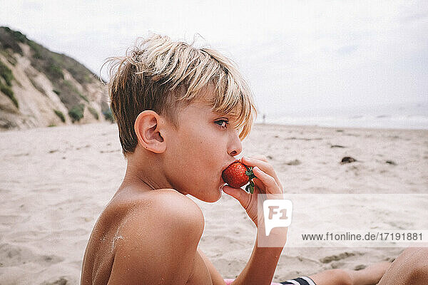 Boy Eating a Strawberry on a Sandy Beach in California