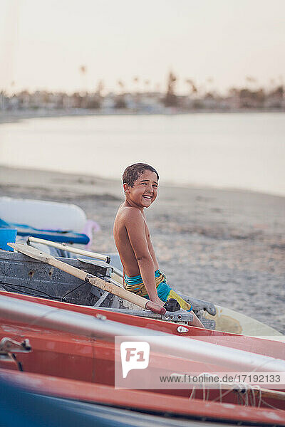 Smiling boy sitting on a docked boat at the beach.