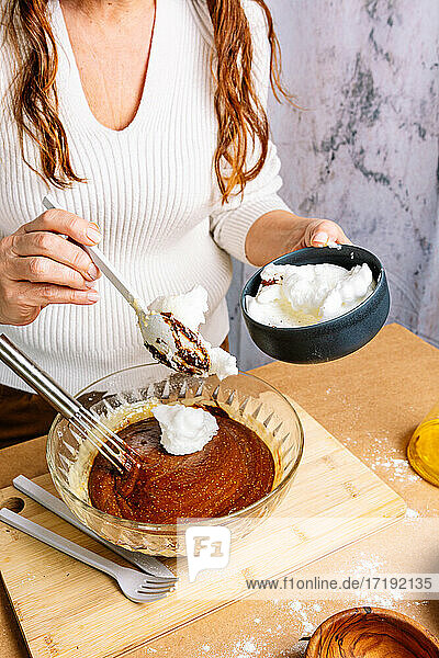 Woman preparing and cooking a chocolate sponge cake.