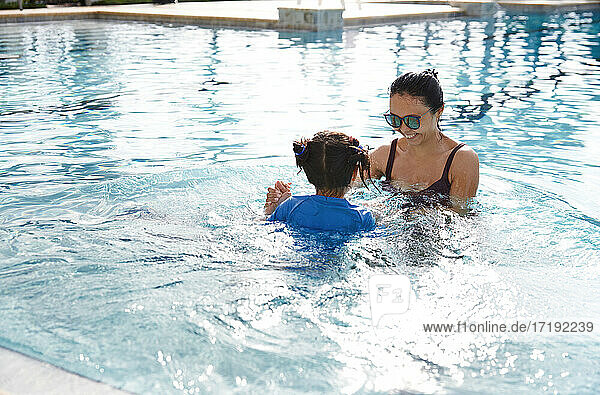 Mother and daughter having fun in swimming pool