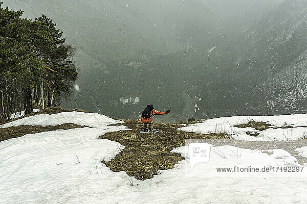 Mann mit Rucksack auf schneebedecktem Berg im Urlaub