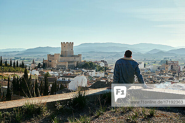 Man sitting on a rooftop overlooking the castle of a city in Spain