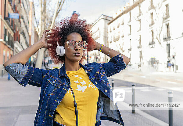 woman with afro hair listening to music with her headphones in the city