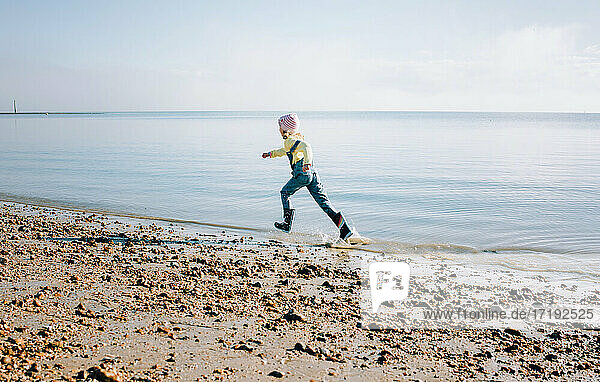 young girl running through the sea happily at the beach in the sun
