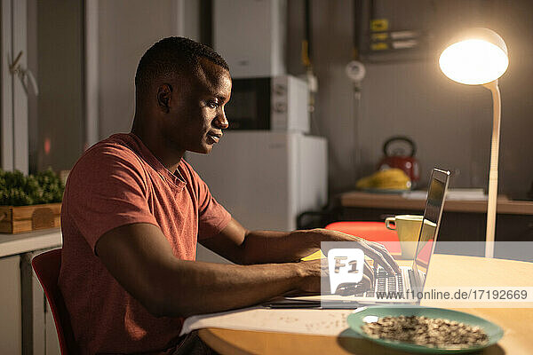 Afroamerikanischer Freiberufler mit Laptop in der Küche