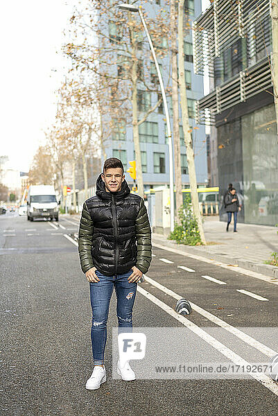 Stilvoller Kerl auf der Straße stehend  die Hand in der Tasche  mit Blick auf die Kamera