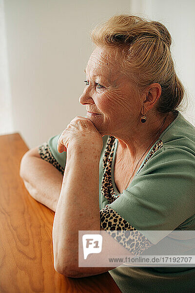 Ältere Frau sitzt am Tisch und lächelt