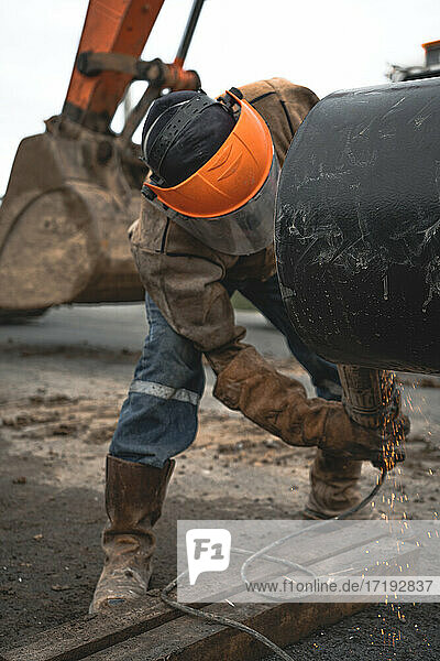 Mann bei Arbeiten an einer Wasserleitung im Freien mit Schutzkleidung