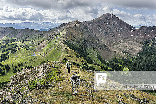 Wanderin mit Hund auf einem Berg gegen bewölkten Himmel