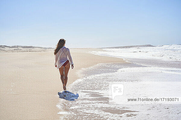 girl from behind walking on a lonely and heavenly beach  enjoying freedom.