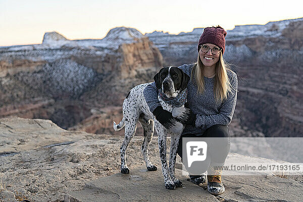 Smiling woman hiking with dog against during vacation
