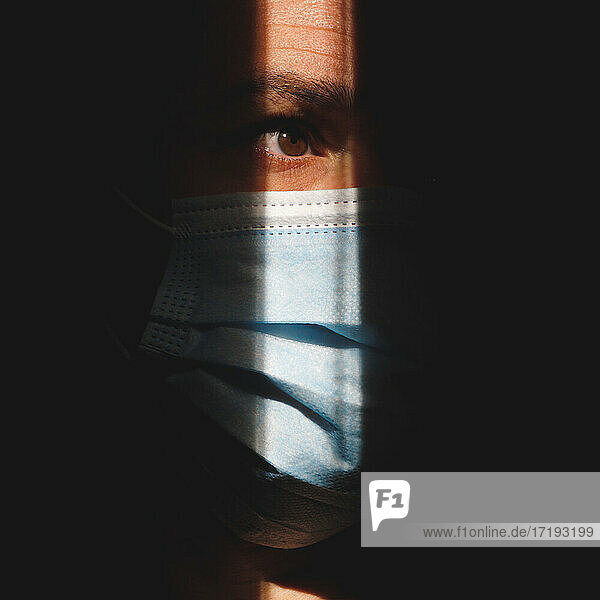 Mann mit Maske im Schatten  der das braune Auge zeigt