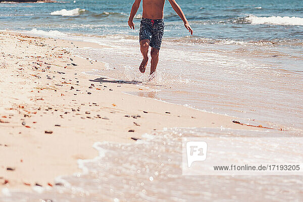 Unterkörper - Junge läuft am Strand.