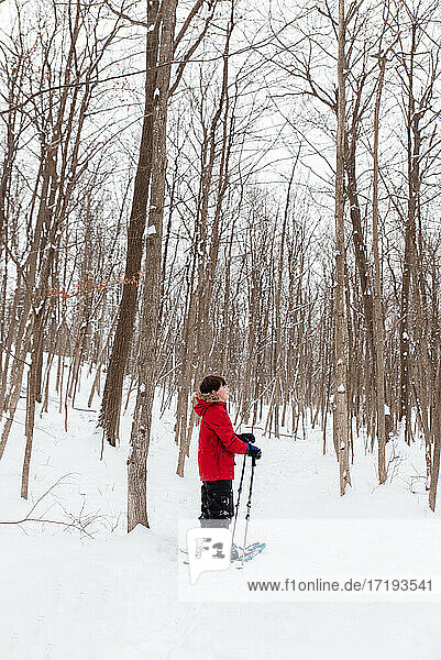 Young boy snowshoeing in the woods on a snowy winter day.