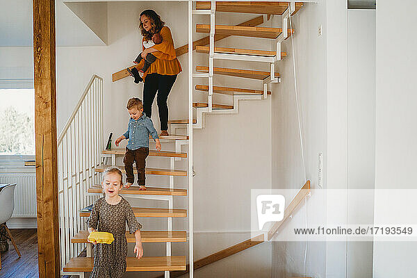 Mutter und Kinder gehen während der Quarantäne die Treppe zu Hause hinunter