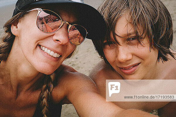 Mutter und Sohn posieren für ein Selfie am Strand