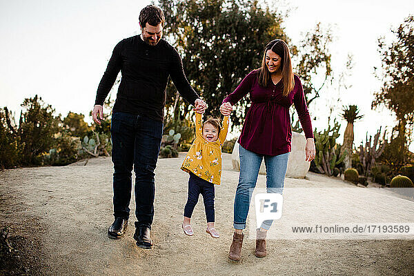 Mama und Papa heben lächelnde Tochter im Kaktusgarten im Balboa Park hoch