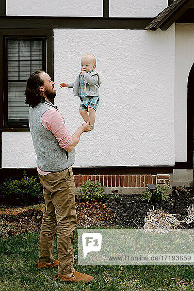 Spaß Vater spielt mit verwirrten Baby Sohn im Vorgarten im Frühjahr