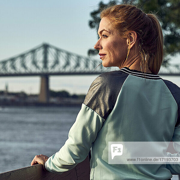 Frau im Park beobachten Sonnenuntergang mit Brücke hinter