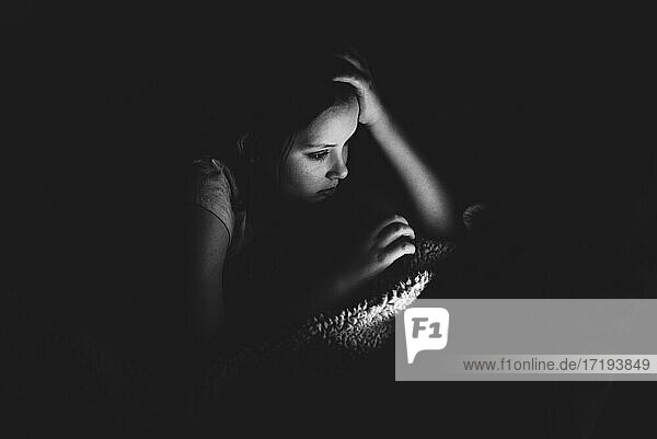Mädchen benutzt ein Tablet in einem dunklen Raum
