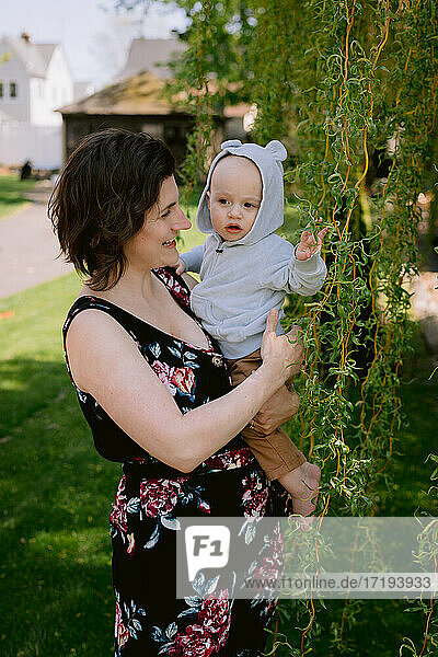 Mother and infant son smiling and playing in front yard in spring