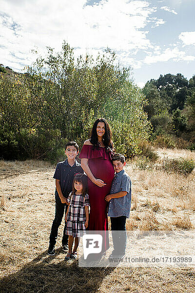 Schwangere Mutter posiert mit drei Kindern auf einem Feld in San Diego