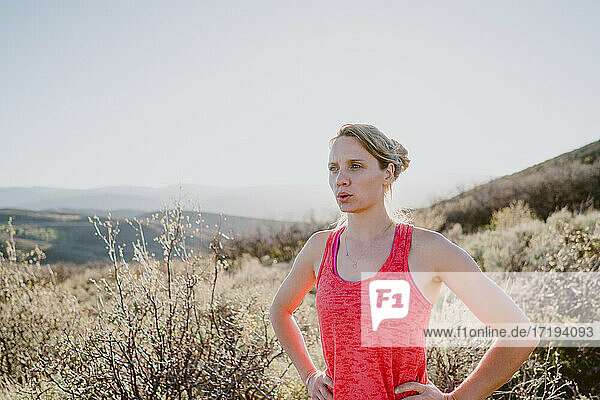 Athletic blonde woman catches her breath on the trail in the mountains
